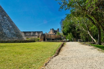 Fototapeta na wymiar Camino de grava que lleva a las ruinas de Uxmal. Vista lateral de la casa del Adivino. Sitio arqueológico de Uxmal, ubicado en Yucatán. Preciosa zona turística. UNESCO Patrimonio de la Humanidad