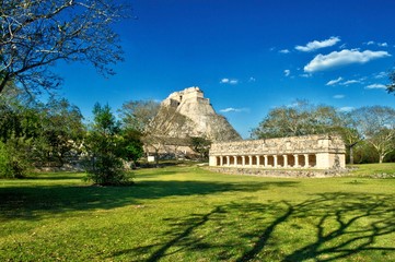 Fototapeta na wymiar Pirámide maya en su totalidad, en el área arqueológica de Uxmal, en la península de Yucatán. Templo maya, con muchas columnas. La casa del Adivino al fondo.