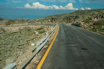 Road over hilly landscape covered by rocks and bushes