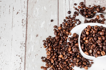 Black coffee in white cup and coffee beans on light wooden background. Top view, space for text