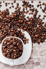 Black coffee in white cup and coffee beans on light wooden background. Top view, space for text