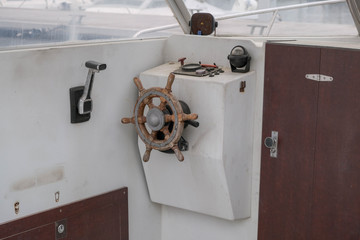 Close up of the helm of the boat, old steering wheel. Cockpit of the small motorboat. Wheelhouse, wood steering wheel, gear lever, compass. Boat service in the port, preparing to sail. © Olga