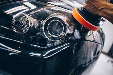 Car detailing - Hands with orbital polisher in auto repair shop. Selective focus.