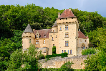 Fototapeta premium Malowniczy zamek w pobliżu wsi pod skałami. Chateau de la Malatrie, La Roque Gageac, Francja