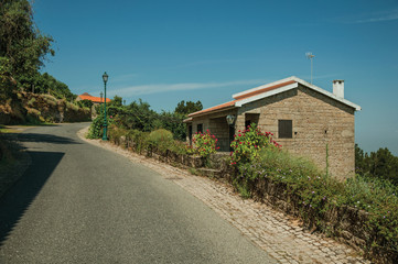 Fototapeta na wymiar Road on slope with stone parapet and rustic house in Monsanto