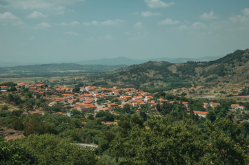 Naklejka na ściany i meble Roofs in hilly landscape covered by rocks and olive tree near Monsanto