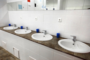 Empty restroom public men bathroom interior with washing hand sinks. Mirror with hand basin in clean toilet.