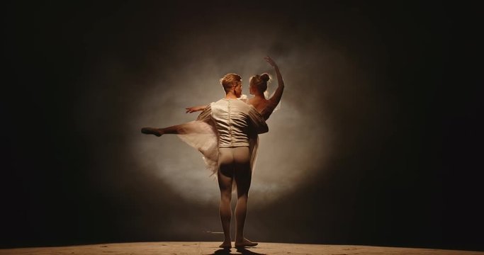 Professional duet of ballet dancers performing on stage isolated on smoked black background. Young choreographers showing their creative art 4k footage