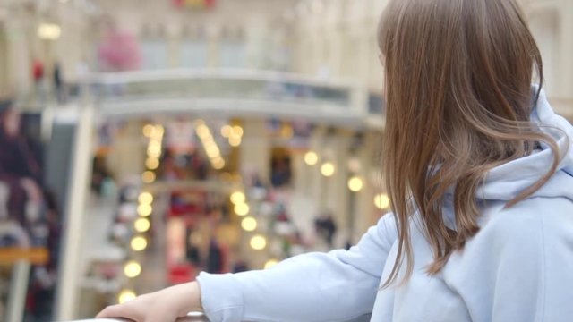 young woman watching around, in a shopping moll, close-up portrait, slow motion