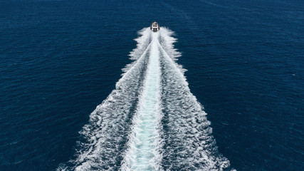 Aerial photo of inflatable rib speed boat cruising in high speed deep blue sea of Mykonos island,...