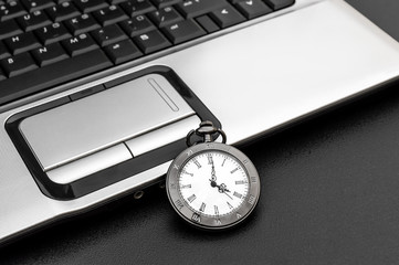 Pocket watch with laptop on the black background.