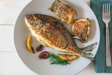 Grilled dorado fish served with lemon and red onion.
