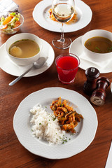 Top view of a set meal business lunch, places on a wooden table: chicken noodle soup, moroccan fried tilapia, chicken with steamed basmati rice