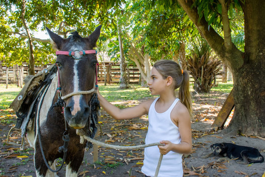 Criança menina cavalgando em fazenda interior