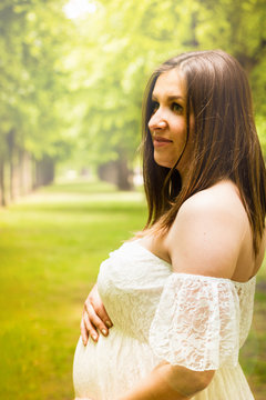 Happy pregnant woman posing over green natural background