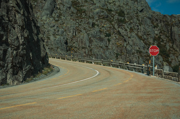 Roadway on rocky landscape with STOP traffic signpost