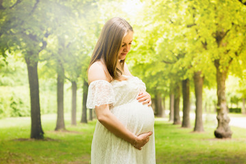 Happy pregnant woman posing over green natural background