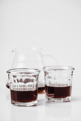 Transparent glass teapot and glasses with tea or coffee on white background