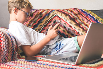 Beautiful smiling teen reading new trend stories online on tablet. Technology addicted young boy watching social video at home. Teenager communicate with generation z remote friend Youth tech concept