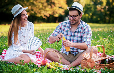 Naklejka na ściany i meble Happy couple enjoying picnic in the park. Love and tenderness, dating, romance, lifestyle concept