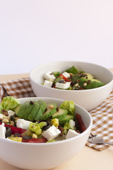 Two bowls of avocado salad with feta cheese on a table with napkin.