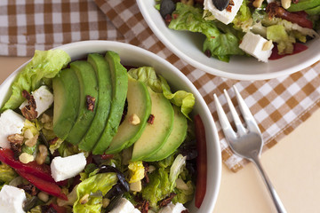 Two bowls of avocado salad with feta cheese on a napkin. Close up, view from above.