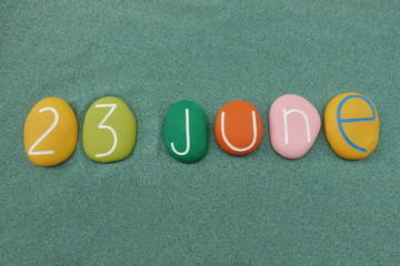 23 June, calendar date composed with multi colored stones over green sand