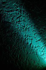 Turquoise diagonal narrow beam of light against a dark background with a pattern