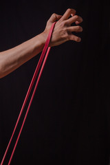 hand of a man exercising with stretching rubber stretching band on a black background in the studio training workout gym