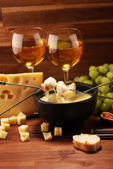 Gourmet Swiss fondue dinner on a winter evening with assorted cheeses on a board alongside a heated pot of cheese fondue