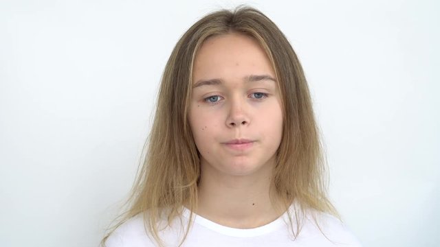 Portrait of a teenage girl with long flowing hair on a white background who stands thoughtfully and licks her lips . Close up.