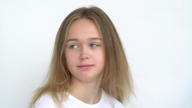 Portrait of a teenage girl with long flowing hair on a white background who is smiling cute wrinkled nose and tongue sticking out spinning in place . Close up.
