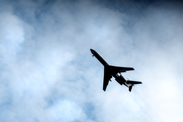 the plane flies across the blue sky