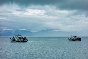 fishing boats in Mid channel between Sao Sebastiao and Ilhabela - São Paulo, Brazil - seen from Ilhabela on a cloudy day