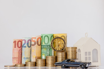 A black model of a car, house and ten, twenty, fifty, one hundred, two hundred and coins euro rolled bills banknotes on white background. Histogram from the euro. Concept of currency growth, savings.