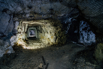 Dark dirty abandoned uranium mine with rusty remnants of railway
