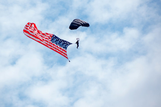 Parachute carries an American flag flying in the sky