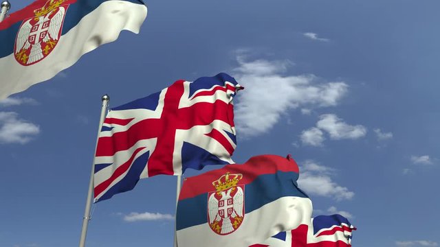 Waving flags of Serbia and the United Kingdom on sky background, loopable 3D animation