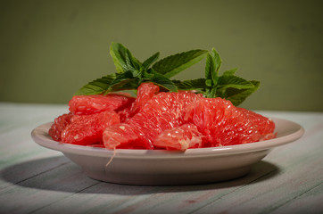 peeled grapefruit in a plate decorated with a sprig of peppermint