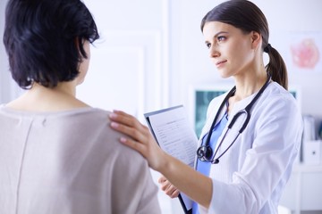 Medical consultation. Female doctor holding a patient by her shoulder, soothing her fear
