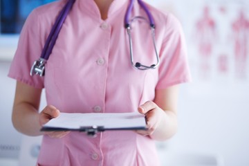 Smiling female doctor with a folder in uniform standing