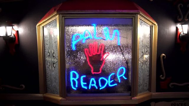 This video shows a flashing neon palm reader fortune teller sign on a caravan window.