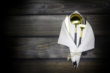 Cutlery in a linen napkin on a wooden dark background. Spoon, fork, knife on a wooden board....
