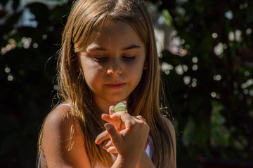 Criança menina observa borboleta com interesse