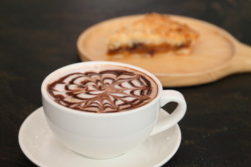 hot chocolate with latte art in white cup on black table and pastry dessert with copy space