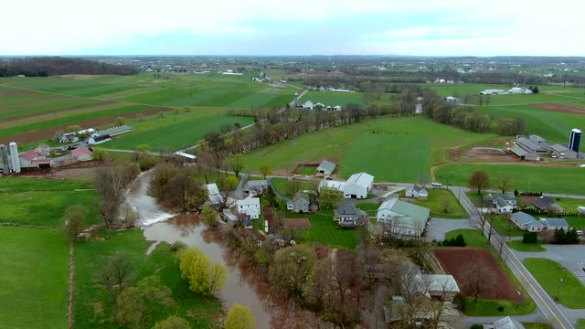 Aerial view of rapids on small river and a covered bridge in American countryside, farms and houses on the banks, Conestoga river and Bitzer's Mill covered bridge in Lancaster county, Pennsylvania