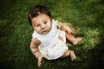 A child sitting by herself that is looking up with distrust and looks worried or abandoned.