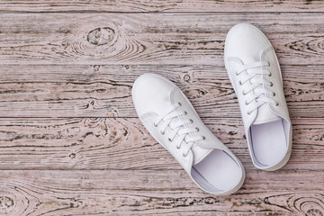 White sneakers on the wooden floor. Sports style. Flat lay.