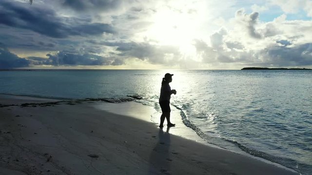 Young girl taking pictures with her camera at sunrise in a beach in Thailand. Another Island can be seen in the distance