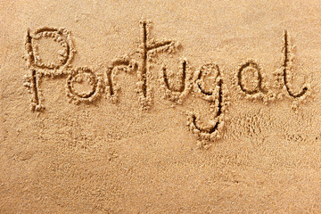 Portugal word written in sand on a sunny portuguese algarve summer beach travel destination sign writing message photo